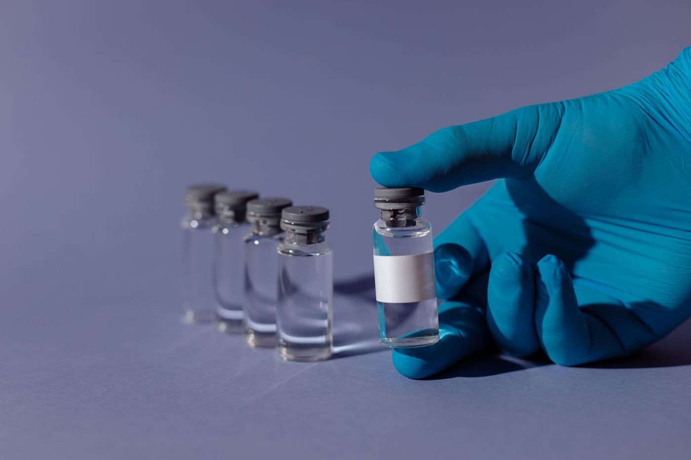 Manos con guantes sosteniendo viales con microplásticos